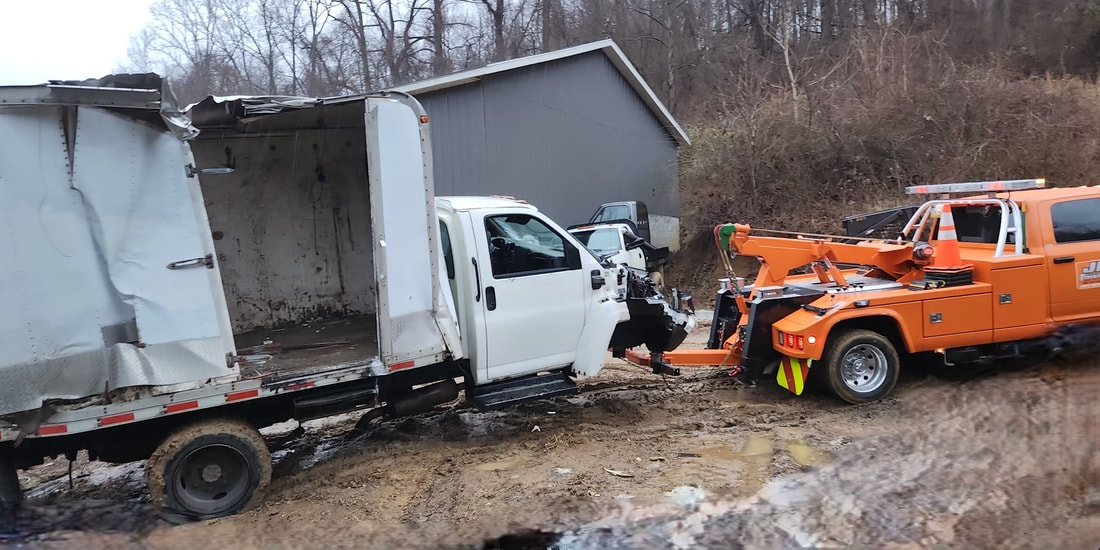 JK Towing's tow truck uses its under-lift boom to tow a severely damaged box truck