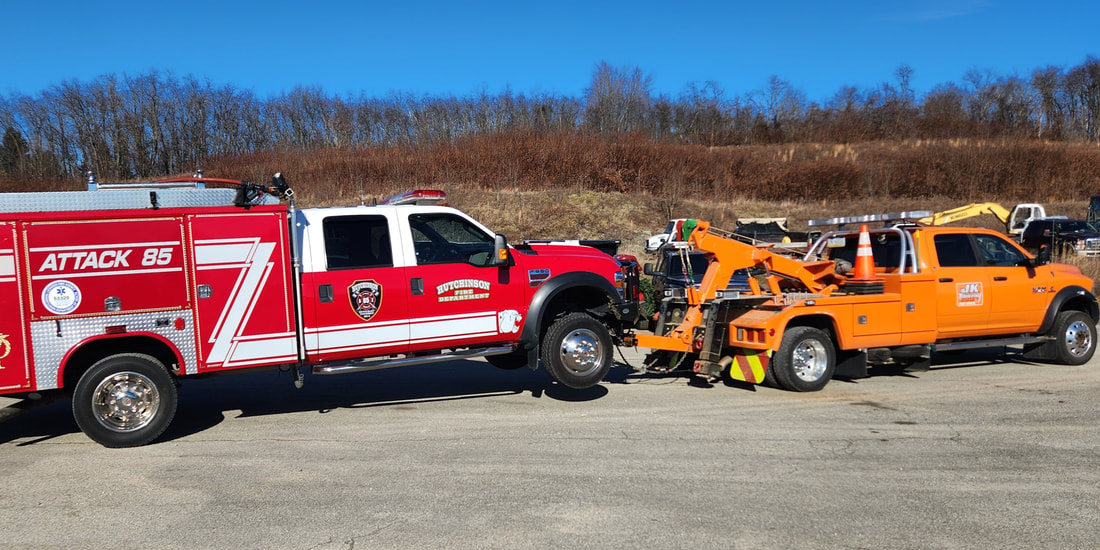 JK Towing's tow truck uses its under-lift boom to tow a firetruck